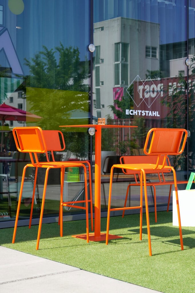 Moderner, orange Stahlmöbelset im Außenbereich vor Glaskasse bei echtstahl.de.